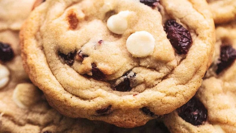 up close pile of cookies with white chocolate chips and cranberry pieces