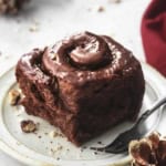 chocolate cinnamon roll on white plate with black fork