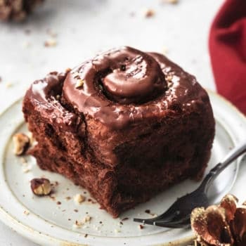 chocolate cinnamon roll on white plate with black fork