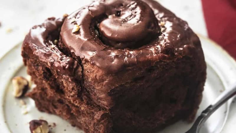 chocolate cinnamon roll on white plate with black fork
