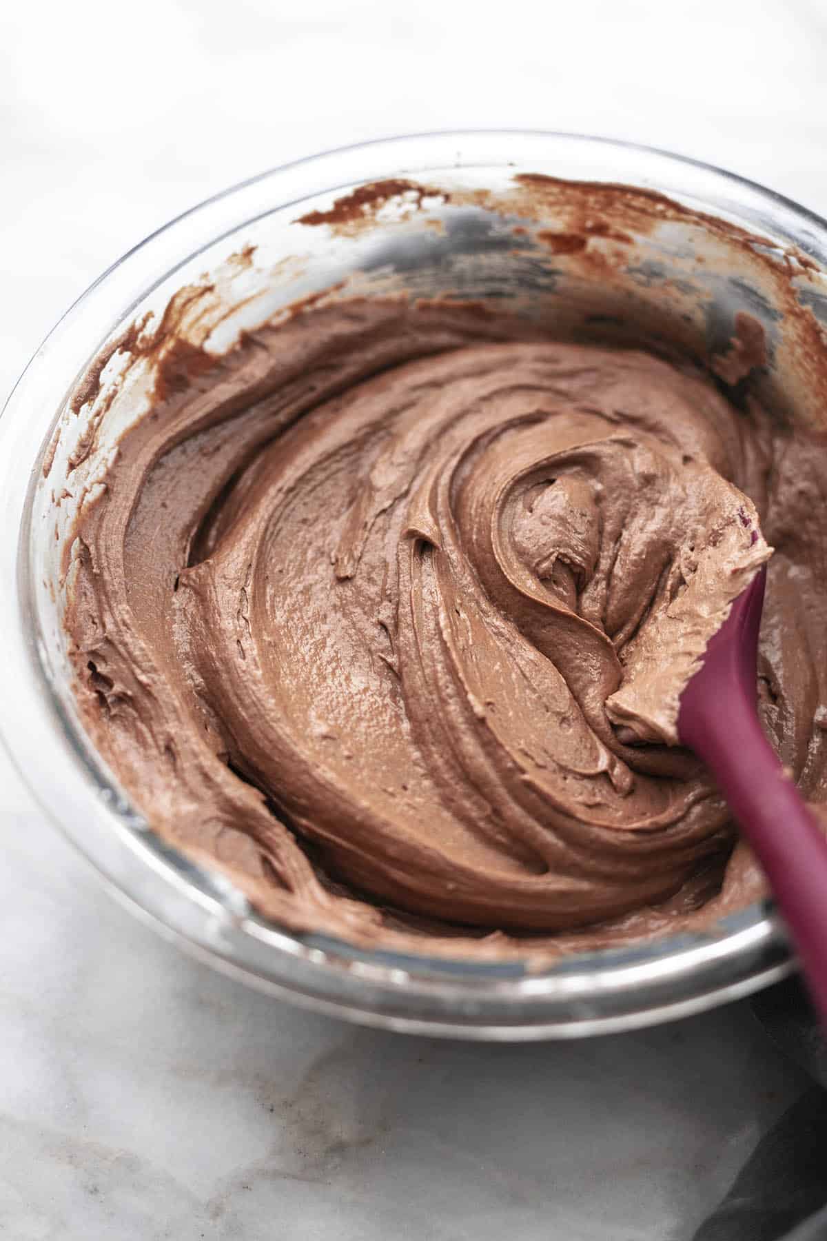 swirled brown icing in glass bowl with spatula