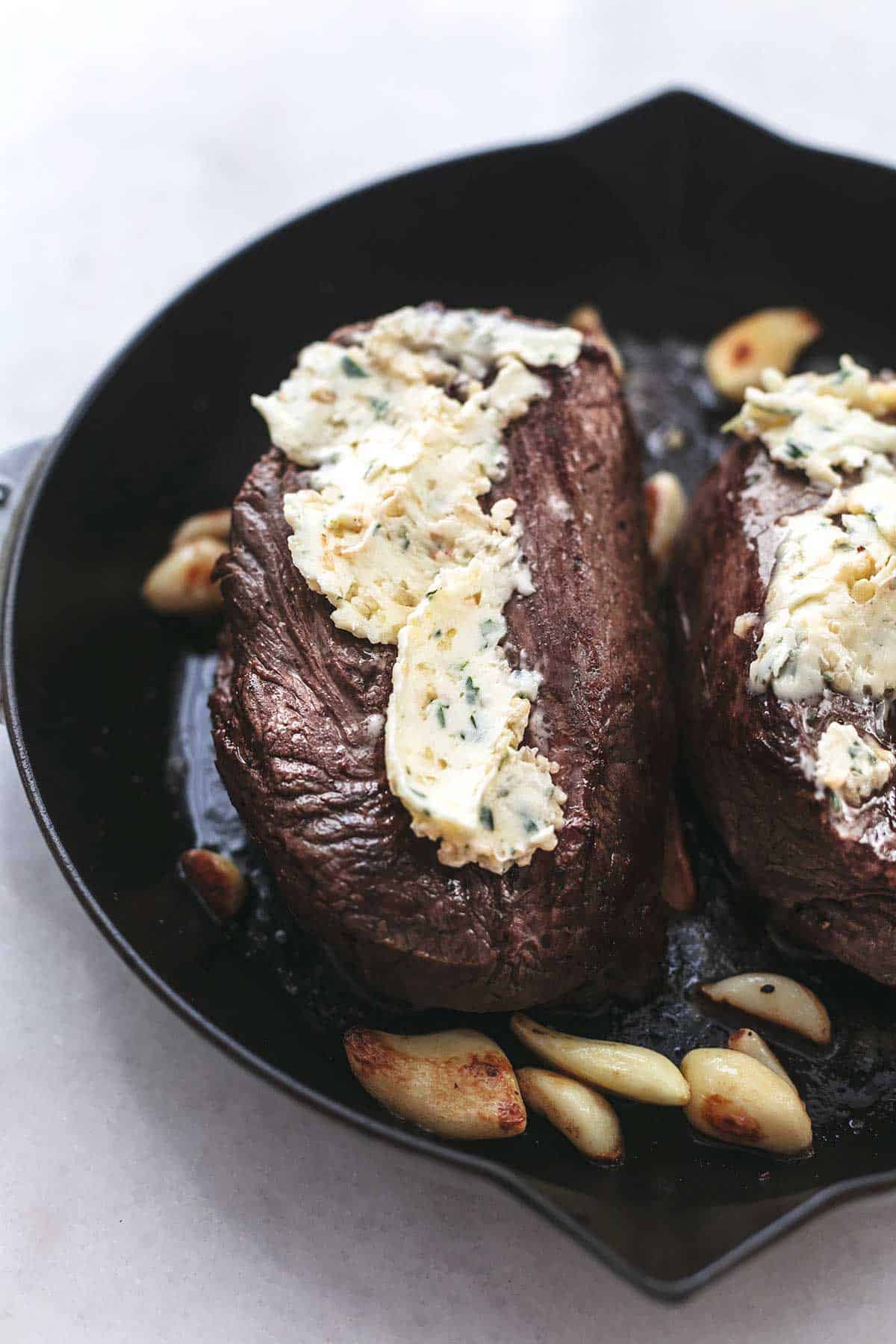 close up of butter spread onto roasted garlic butter beef tenderloin in a skillet.