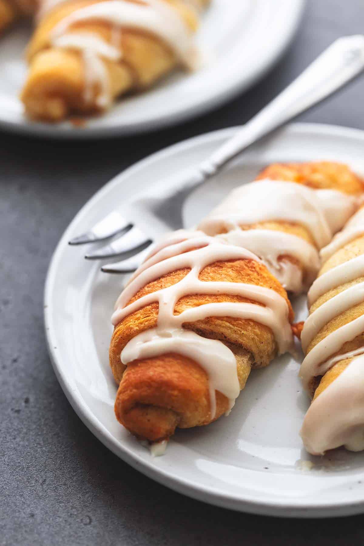 close up of cinnamon roll ups with a fork on a plate.
