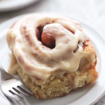 cinnamon roll with white icing on white plate