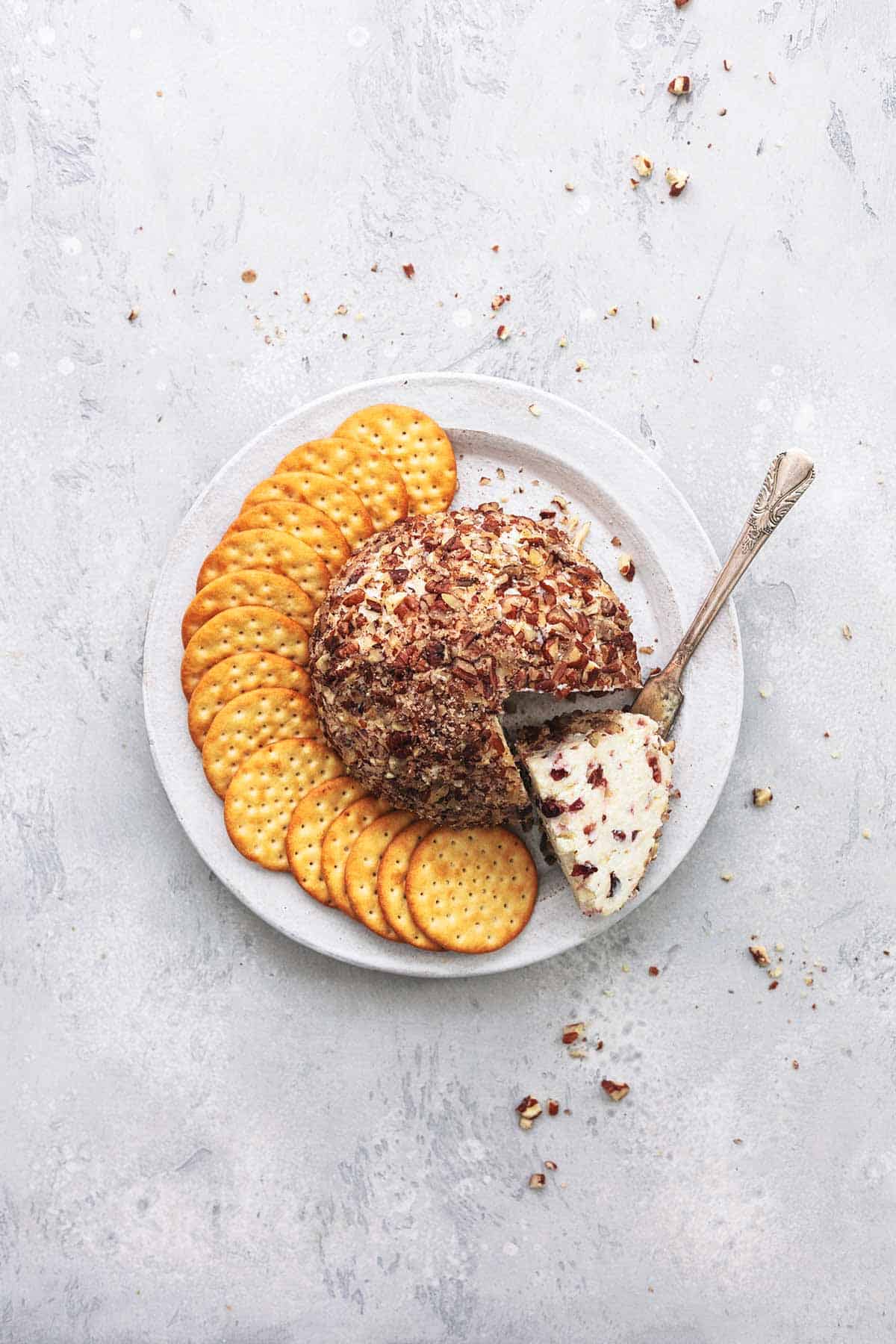 top view of cranberry pecan cheeseball with crackers on a plate.