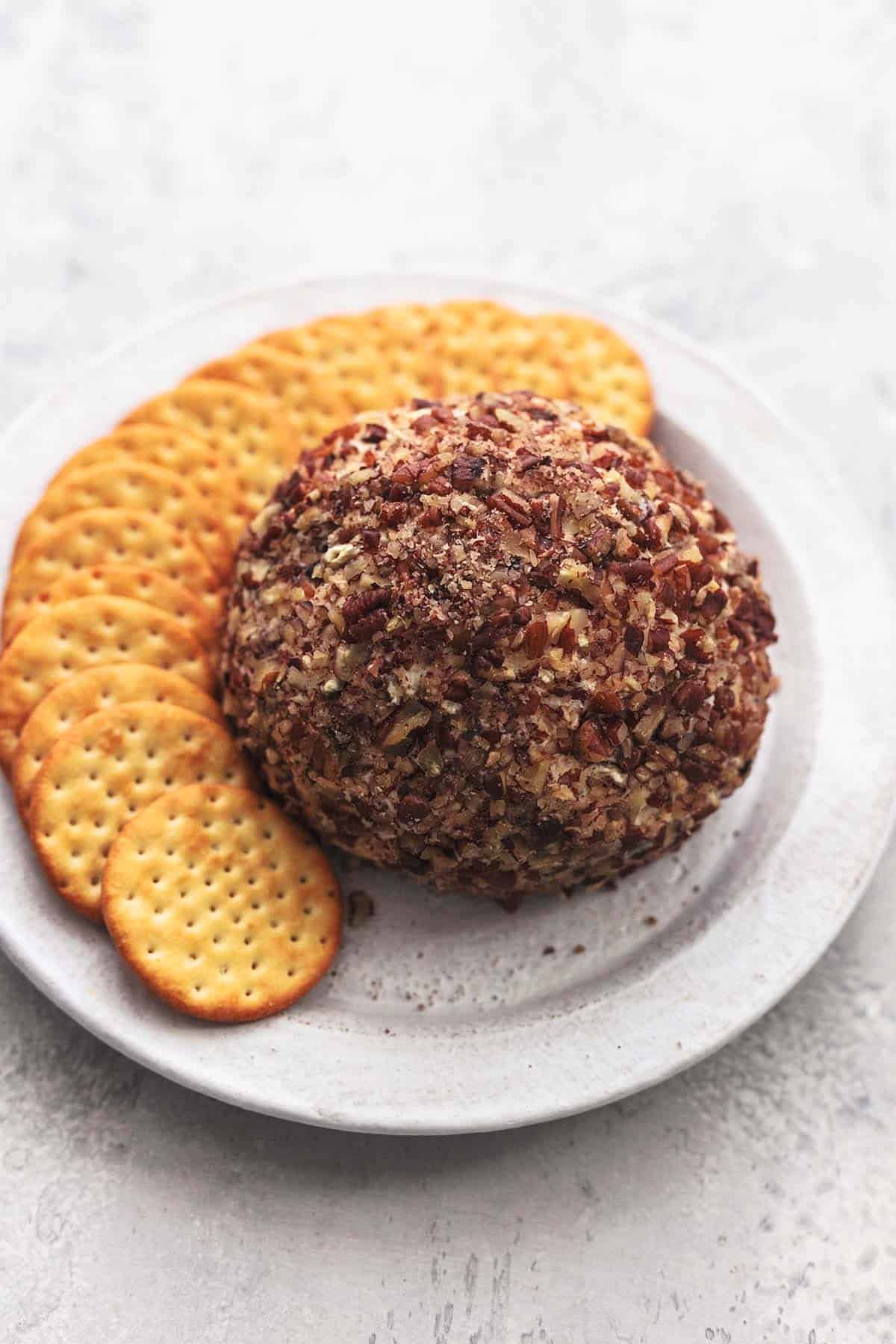 a cranberry pecan cheeseball with crackers on a plate.