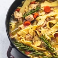 chicken and noodles in broth with vegetables in red stock pot