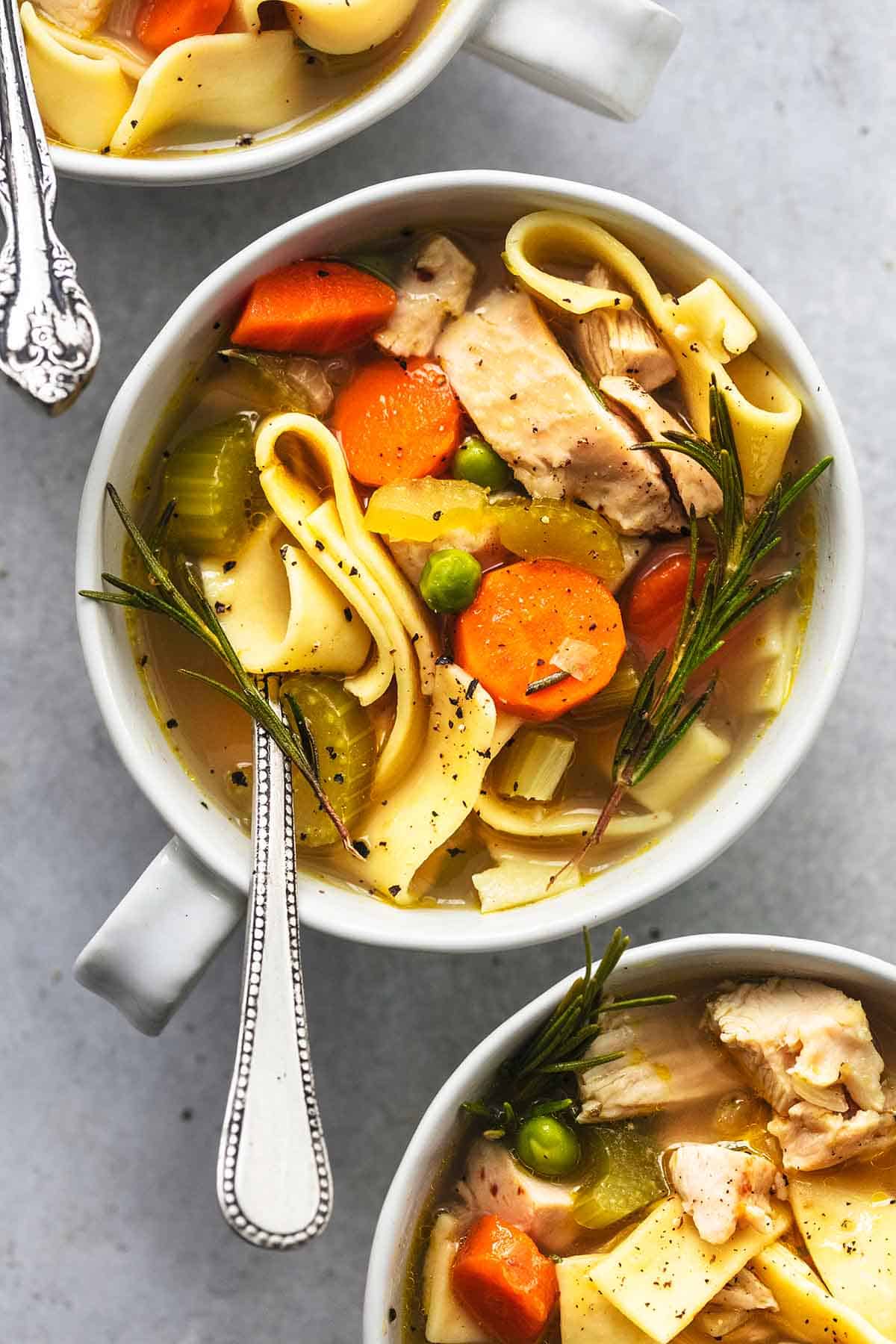 top view of small bowls of chicken noodle soup with spoons.