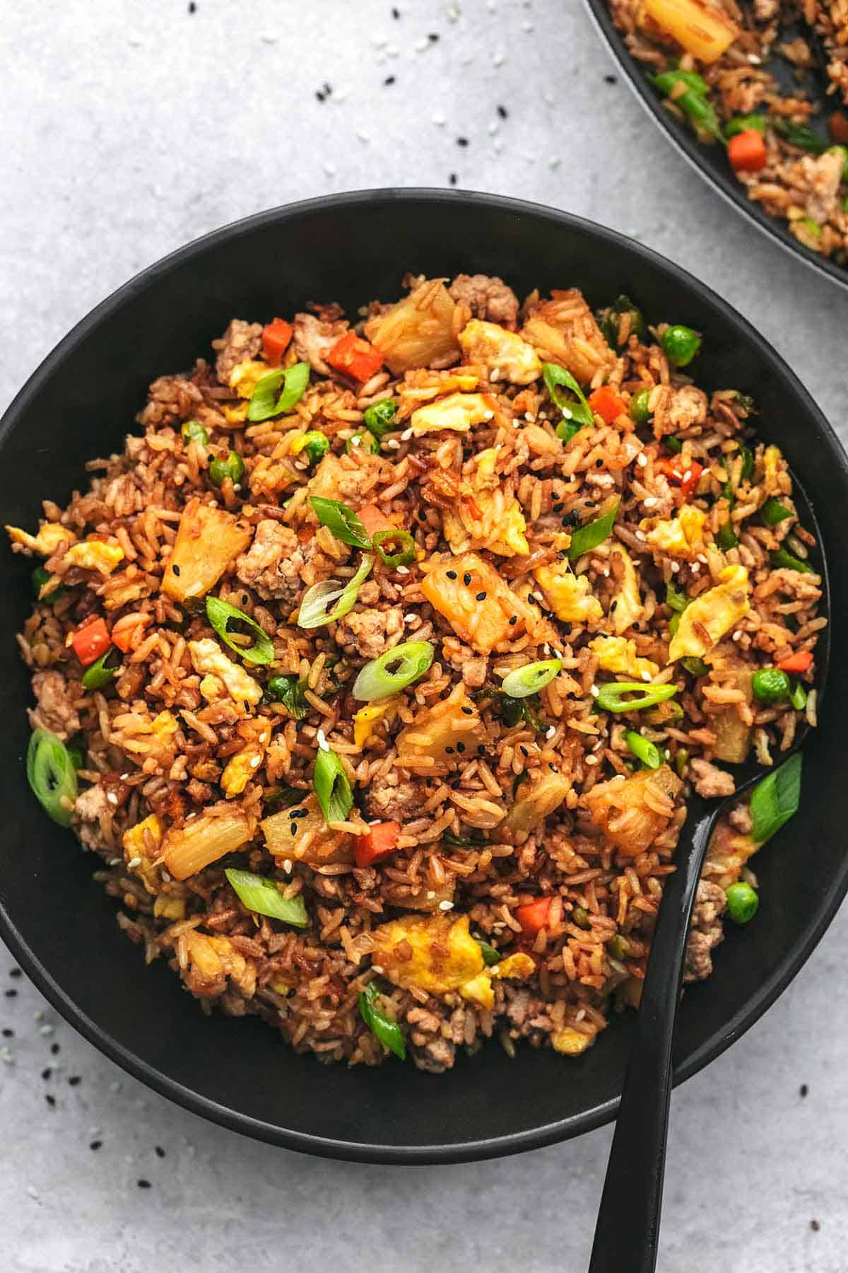 overhead view of rice and veggies with pineapple and pork in black dish