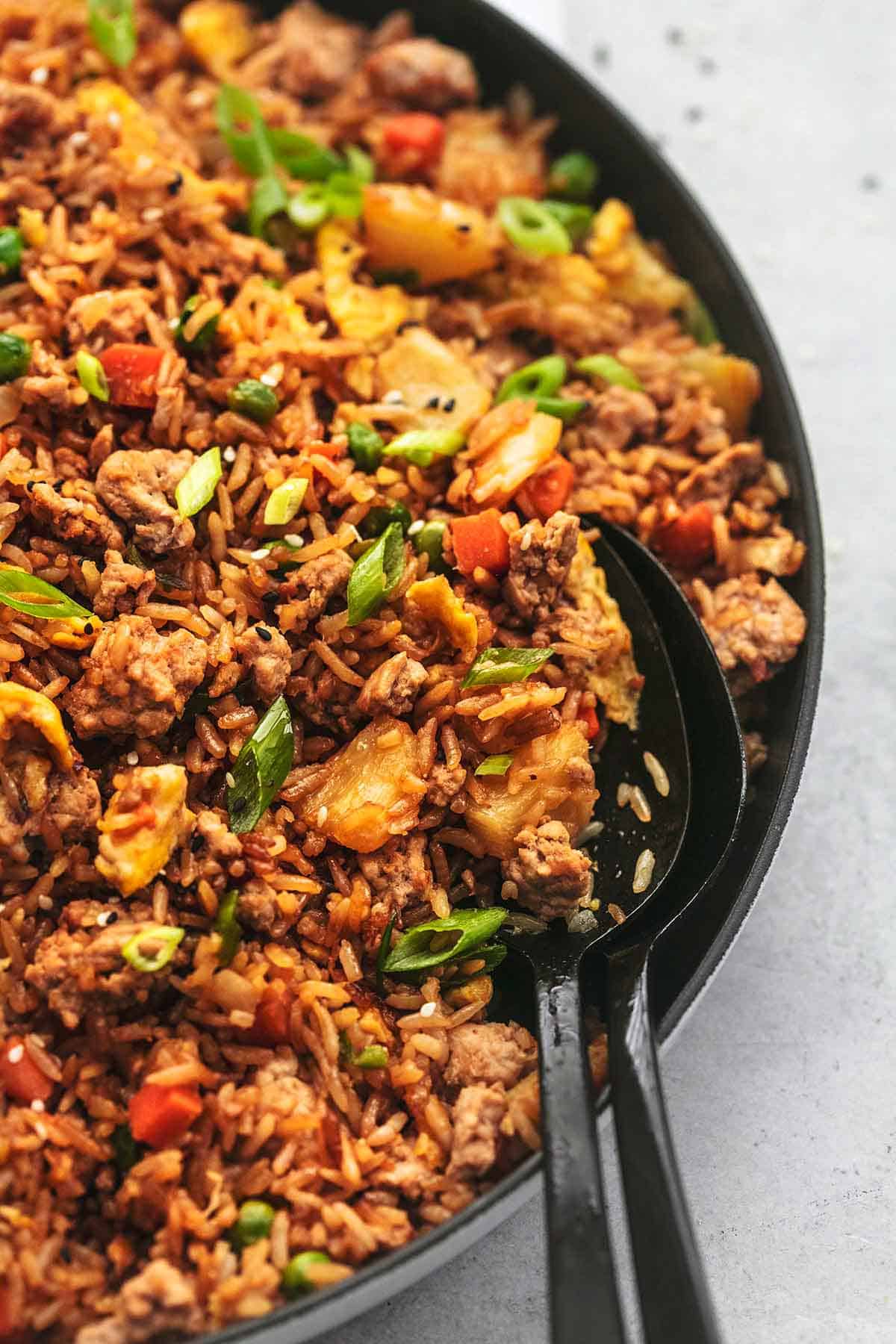 close up of pork fried rice with two serving spoons in a skillet.