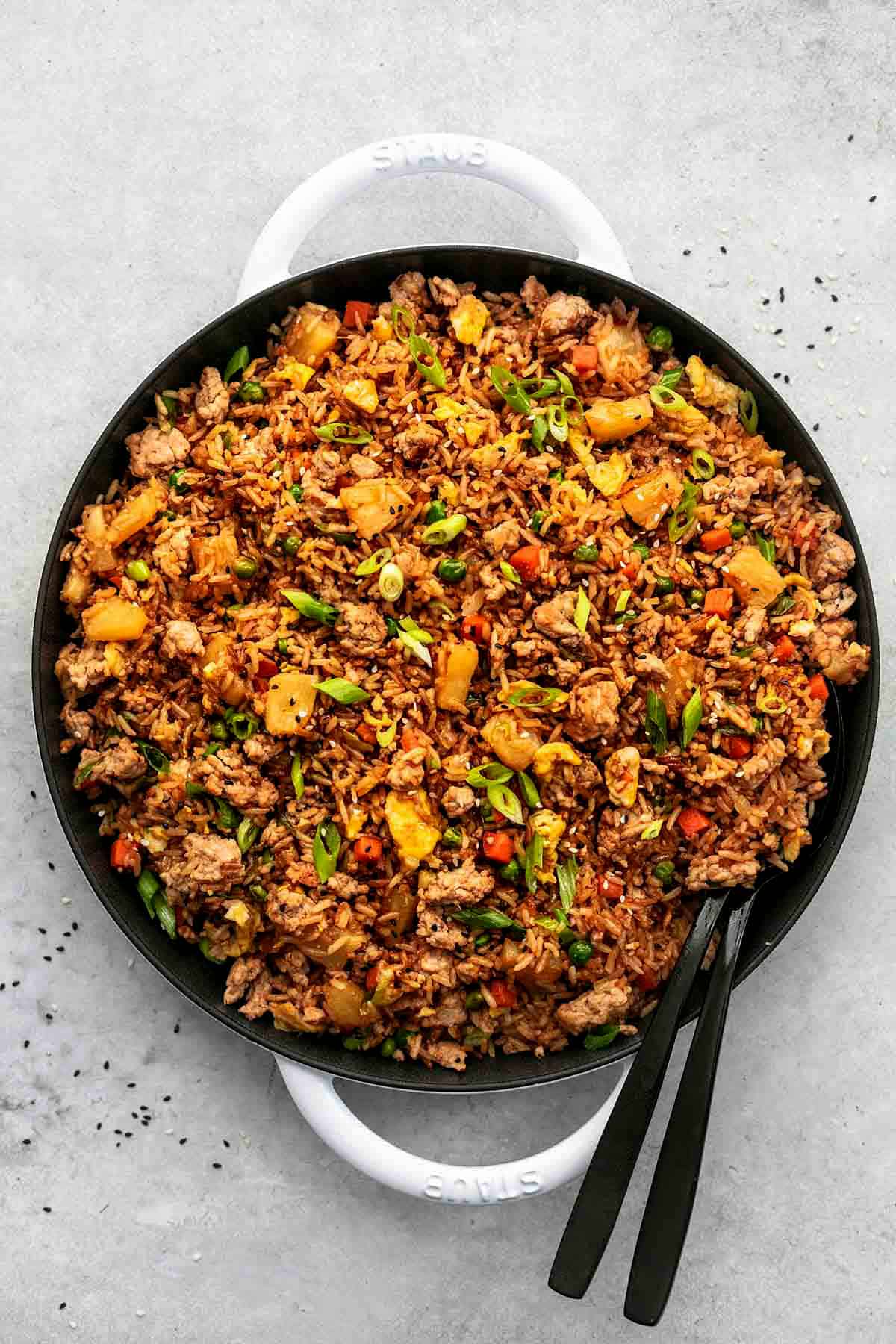 top view of pork fried rice with two serving spoons in a skillet.