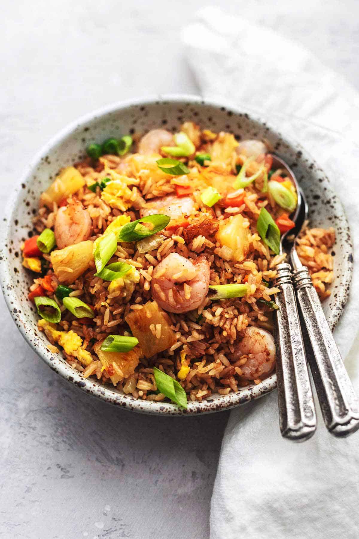 close up of shrimp fried rice in a bowl with two spoons.