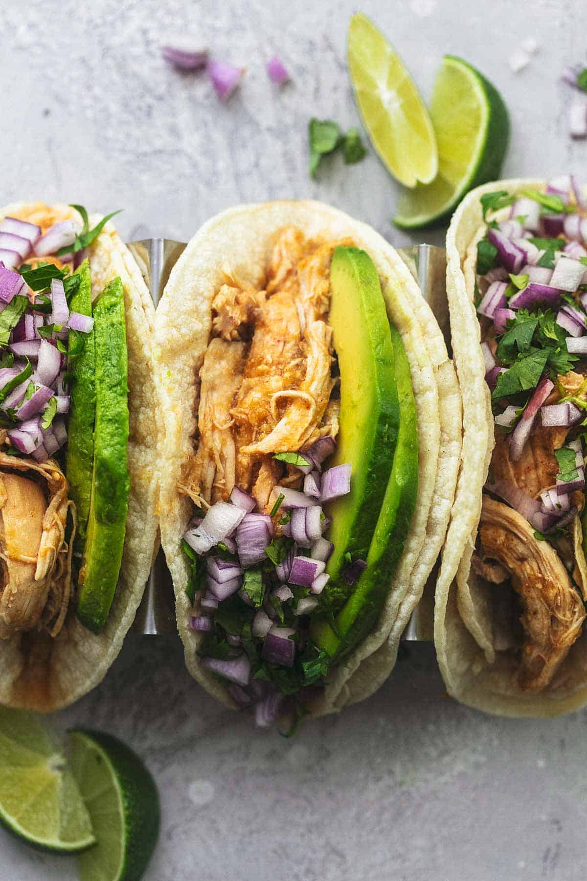 close up top view of chicken tacos with lime slices on the side.