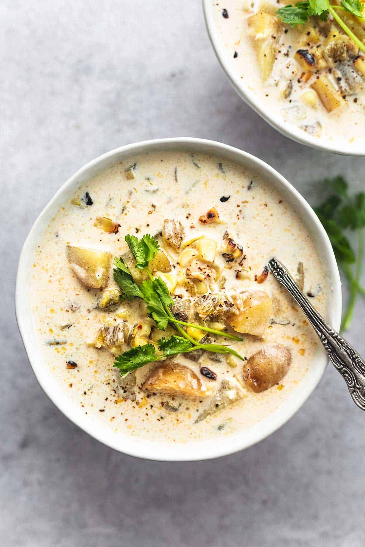 corn chowder with potatoes and cilantro in bowl with spoon