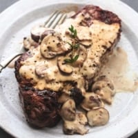 cooked steak on plate topped with creamy mushroom sauce