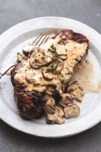 cooked steak on plate topped with creamy mushroom sauce