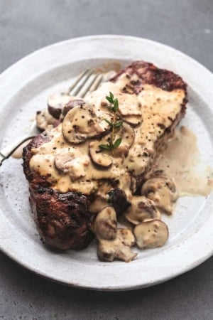 cooked steak on plate topped with creamy mushroom sauce