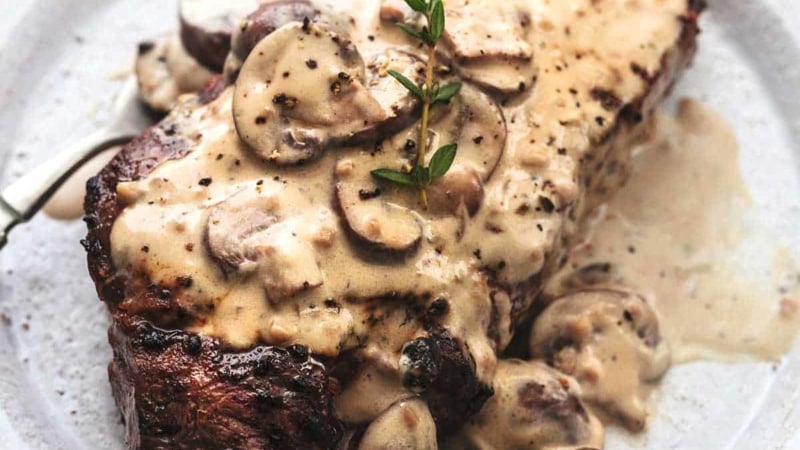 cooked steak on plate topped with creamy mushroom sauce