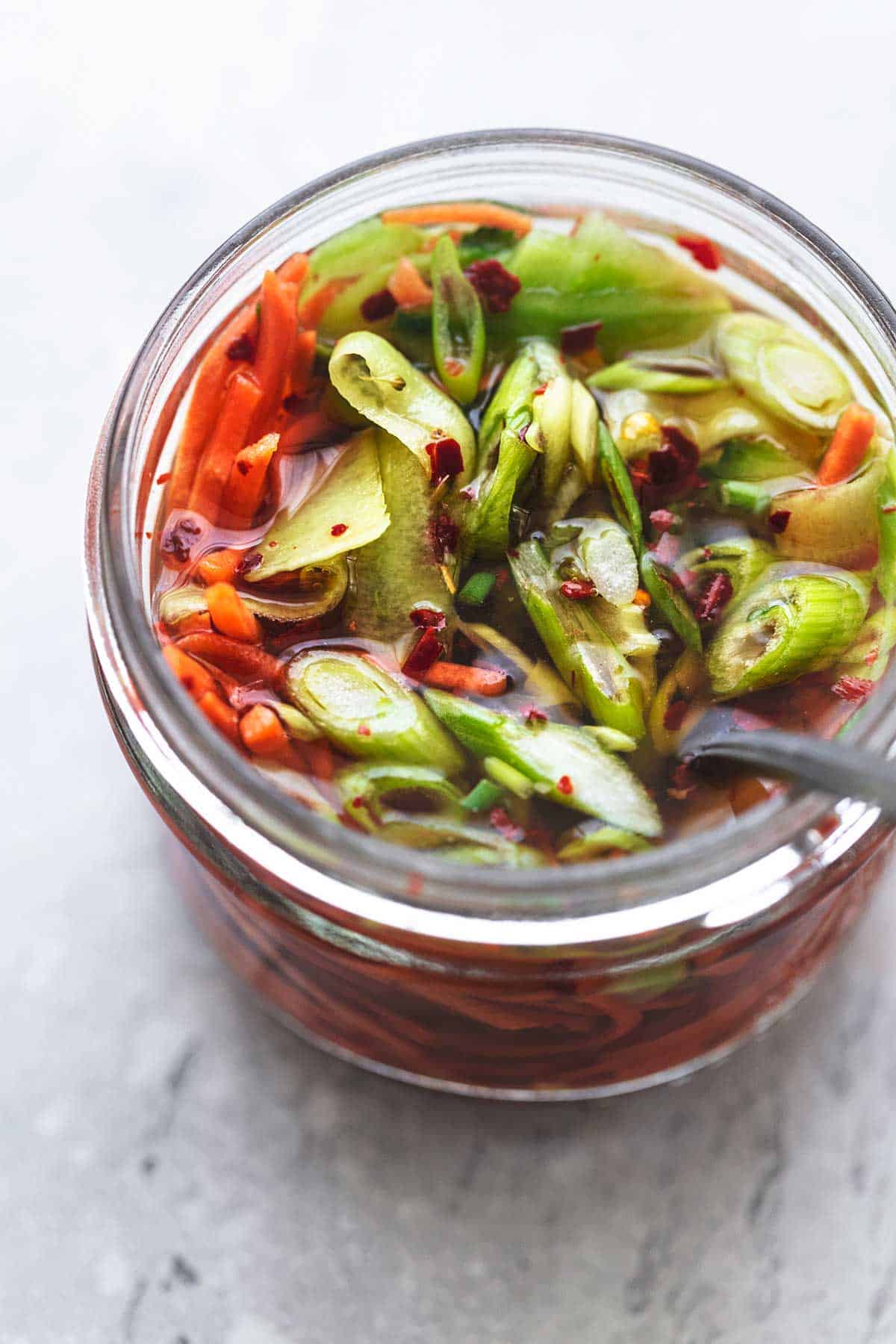 marinated vegetables with carrots, onions, and red pepper flakes in a glass jar.