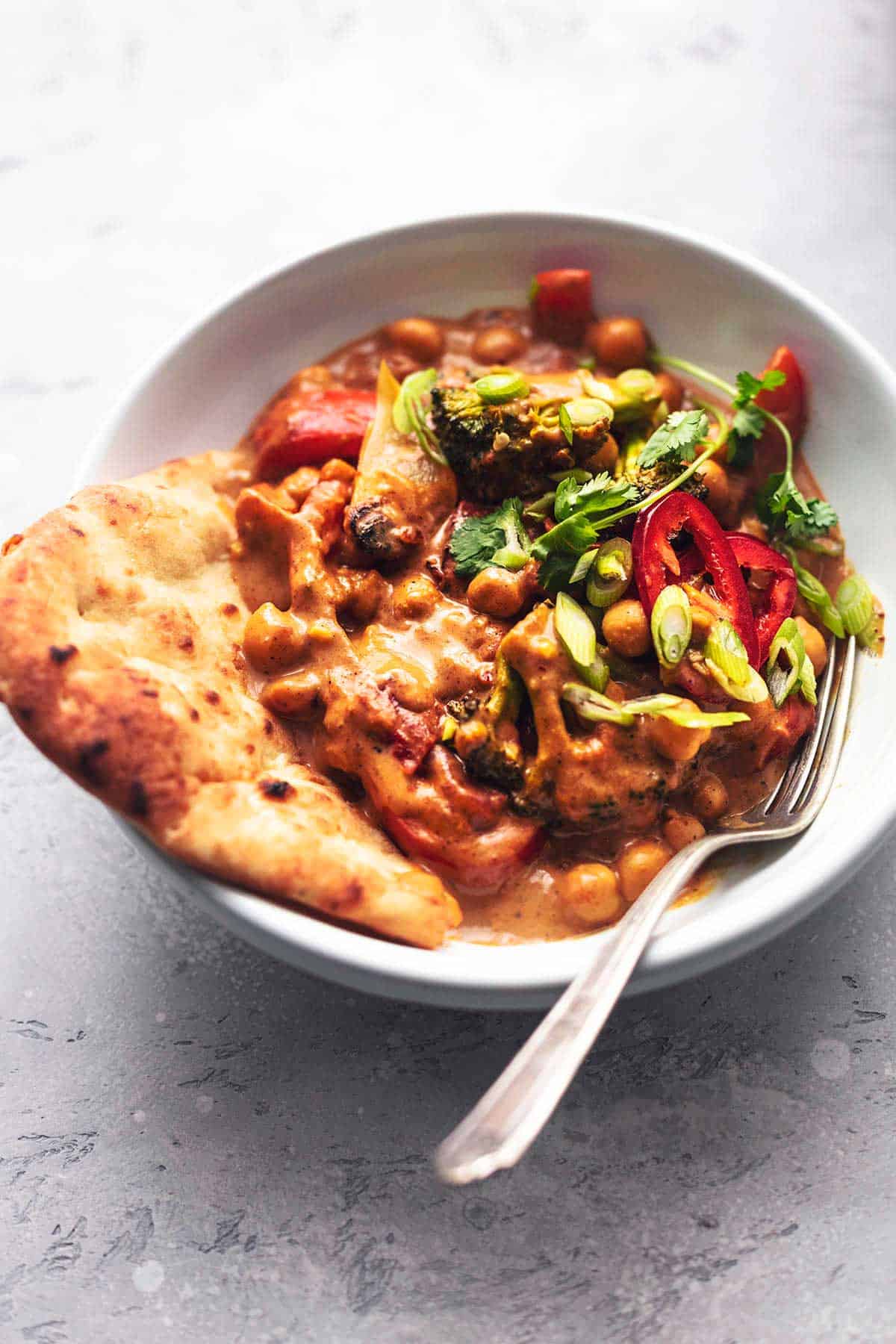 vegetables in red sauce with bread in white bowl with fork