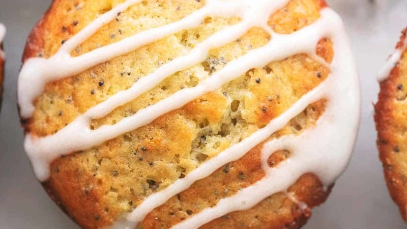 overhead view of muffins with poppy seeds, lemon wedges, and lemon glaze