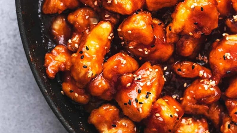 chicken pieces cooked in red brown sauce in black skillet