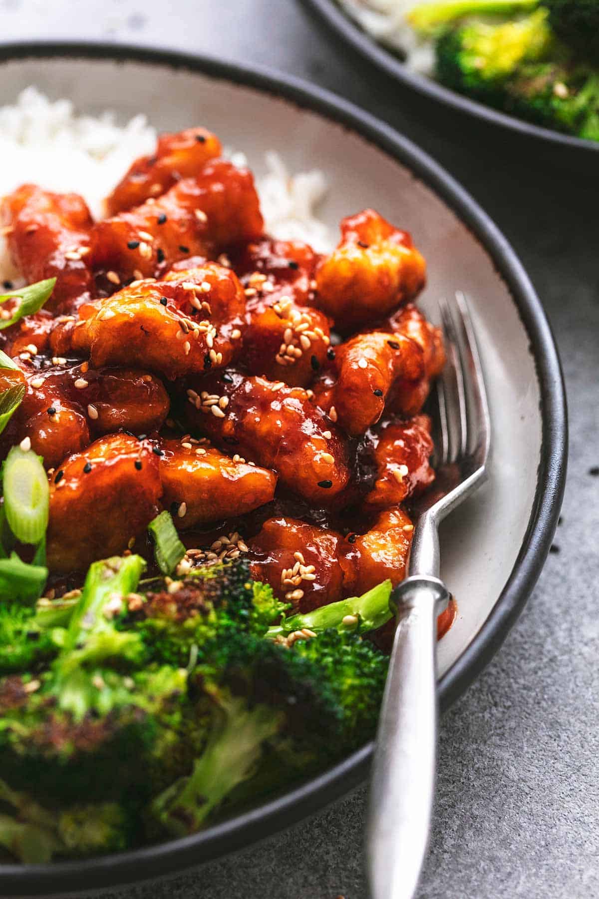 chicken bites in red-brown sauce with silver fork on white and black plate