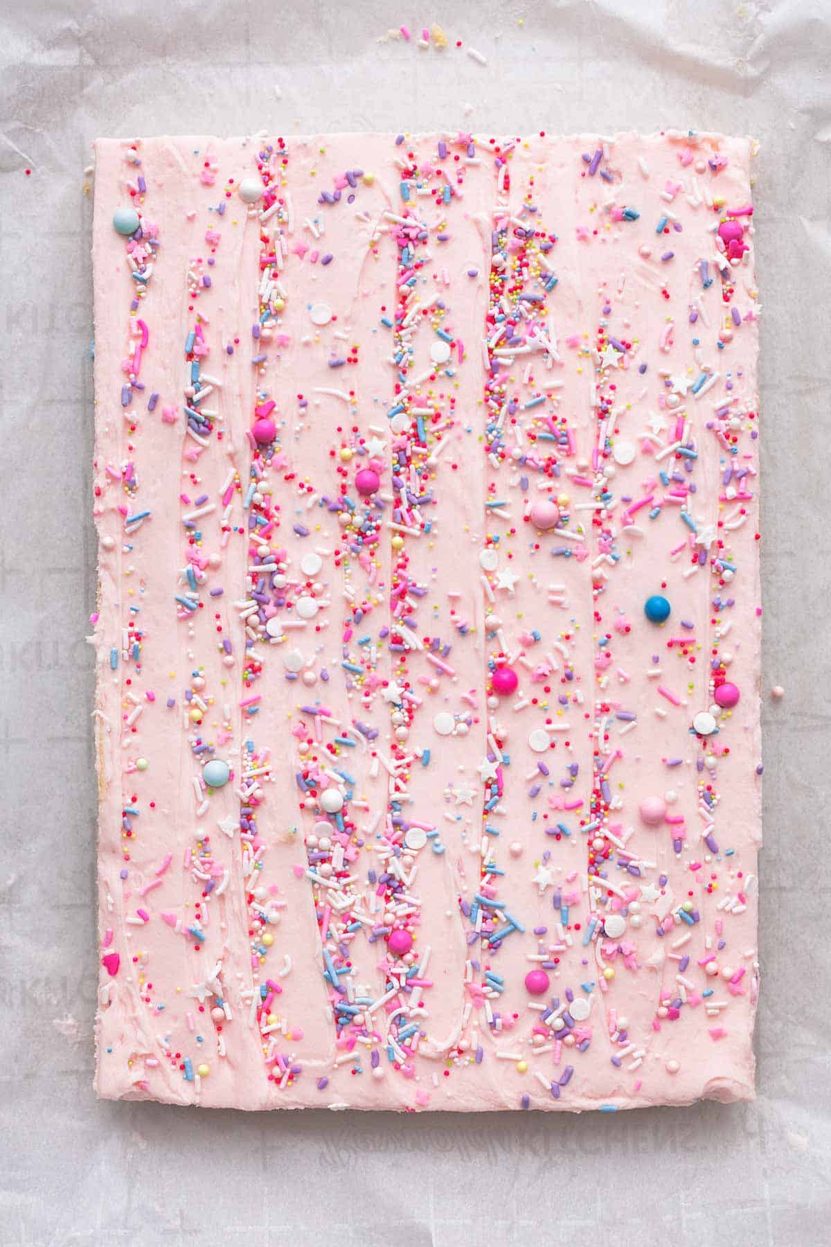 overhead view of frosted rectangle dessert with pink frosting and sprinkles