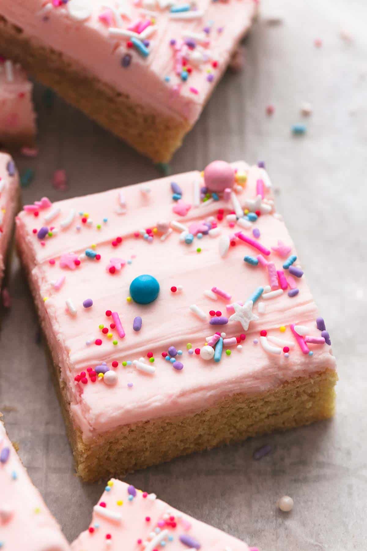 close up of a sugar cookie bar with sprinkles on top with more bars on the side.