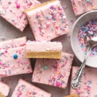 overhead view of dessert bars with sugar cookie base and buttercream frosting on top with bowl of sprinkles