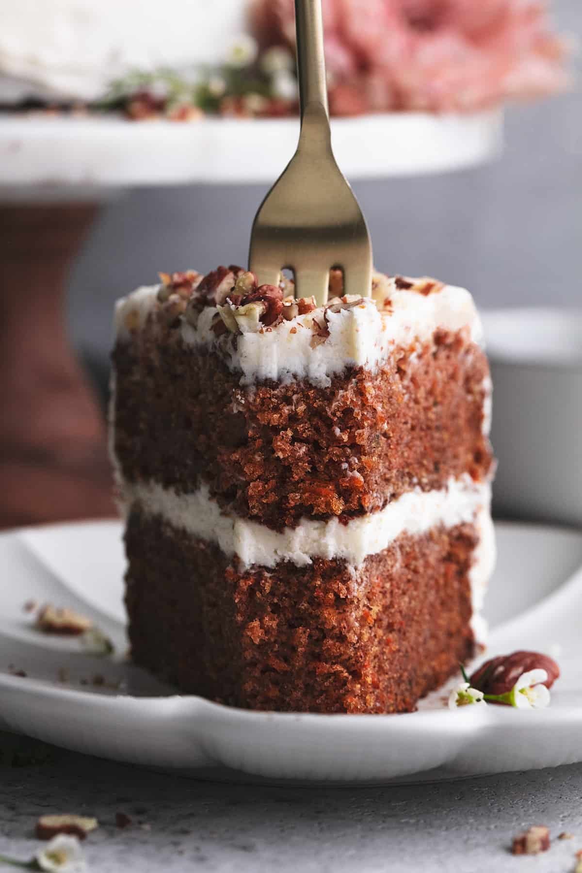fork cutting into slice of carrot cake on a plate