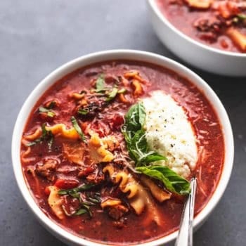 lasagna soup in bowl with spoon, ricotta, and fresh basil garnish