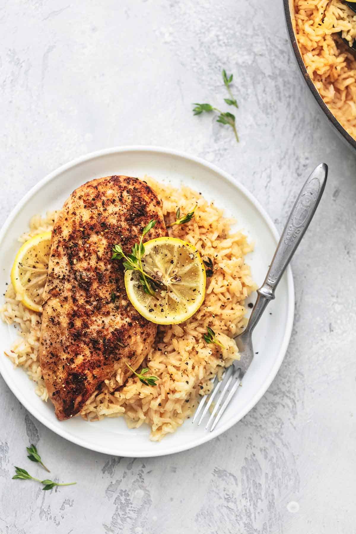 top view of lemon herb chicken and rice with a fork on a plate.