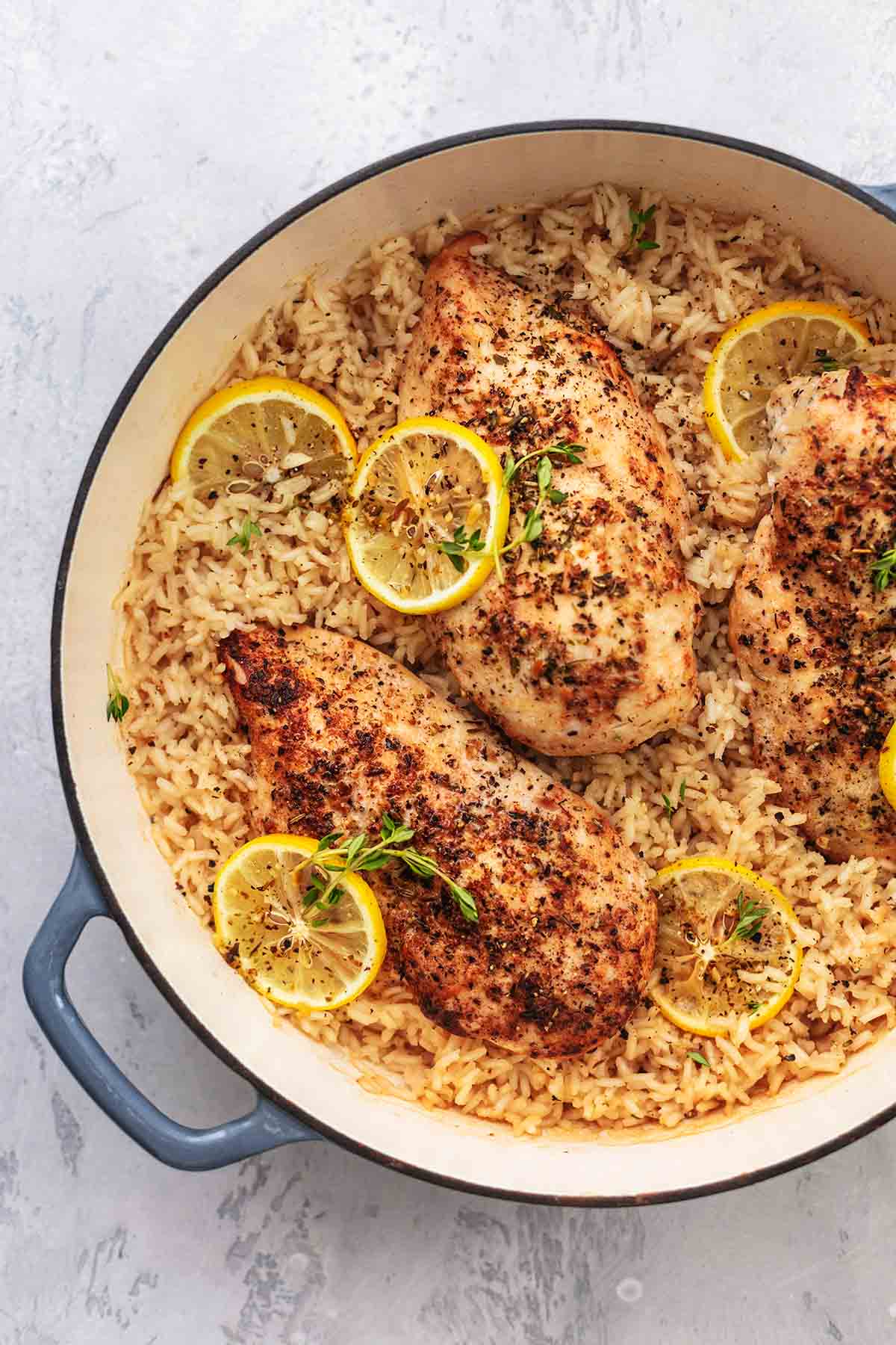 top view of lemon herb chicken and rice with lemon wheels in a skillet.