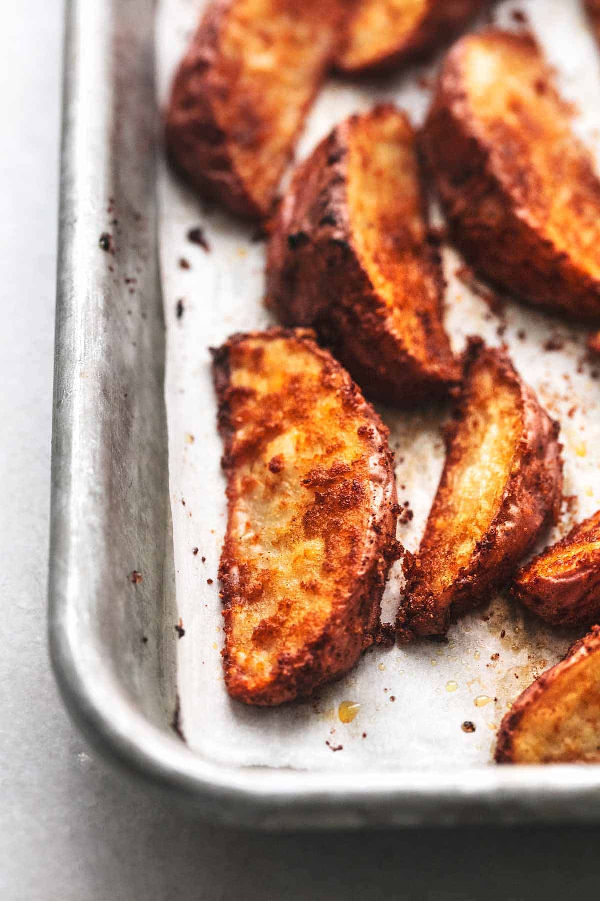 close up view of several seasoned potato wedges on baking sheet