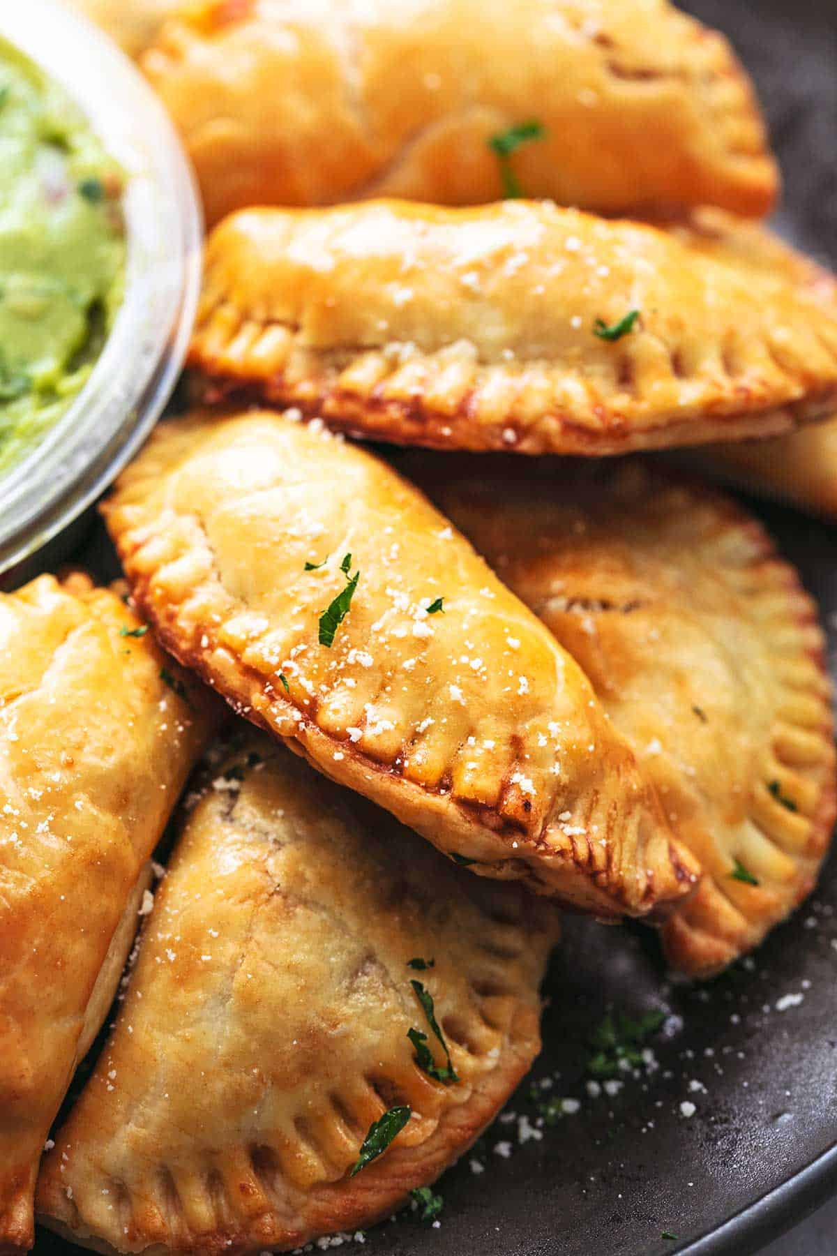 up close baked empanadas piled on a plate