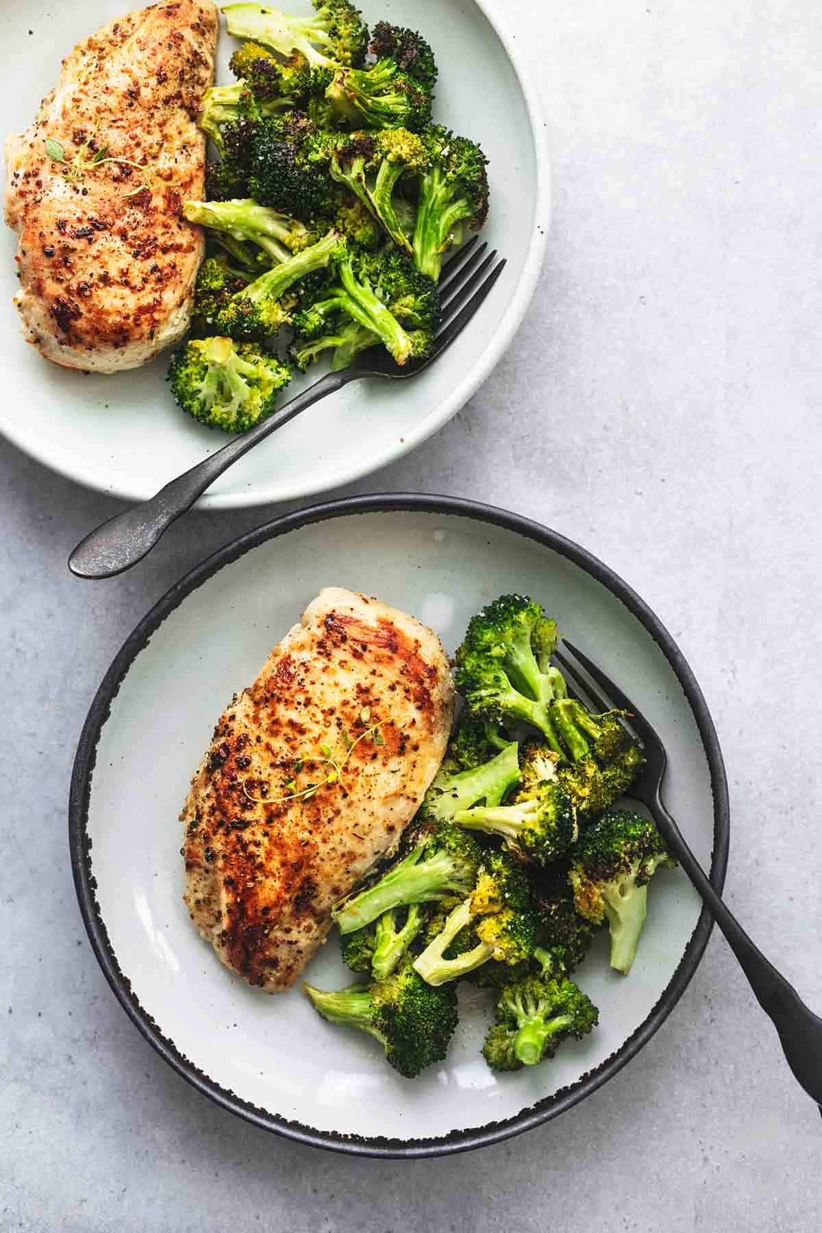 overhead view of one whole, and one partial plate of chicken and broccoli with forks