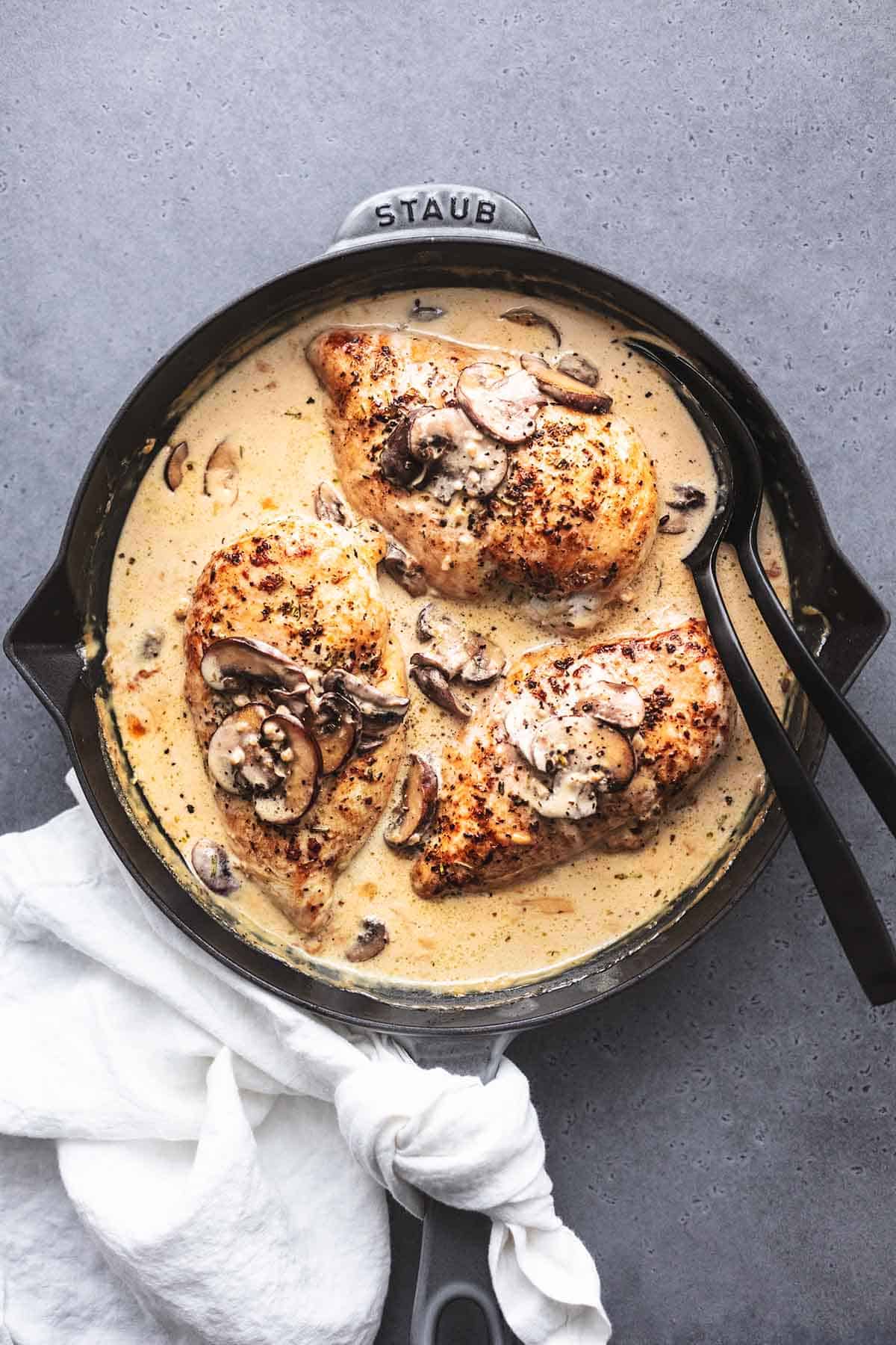 overhead view of mushroom cream sauce for chicken in skillet with serving spoons