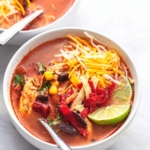 white bowl with chicken tortilla soup with shredded cheese on top