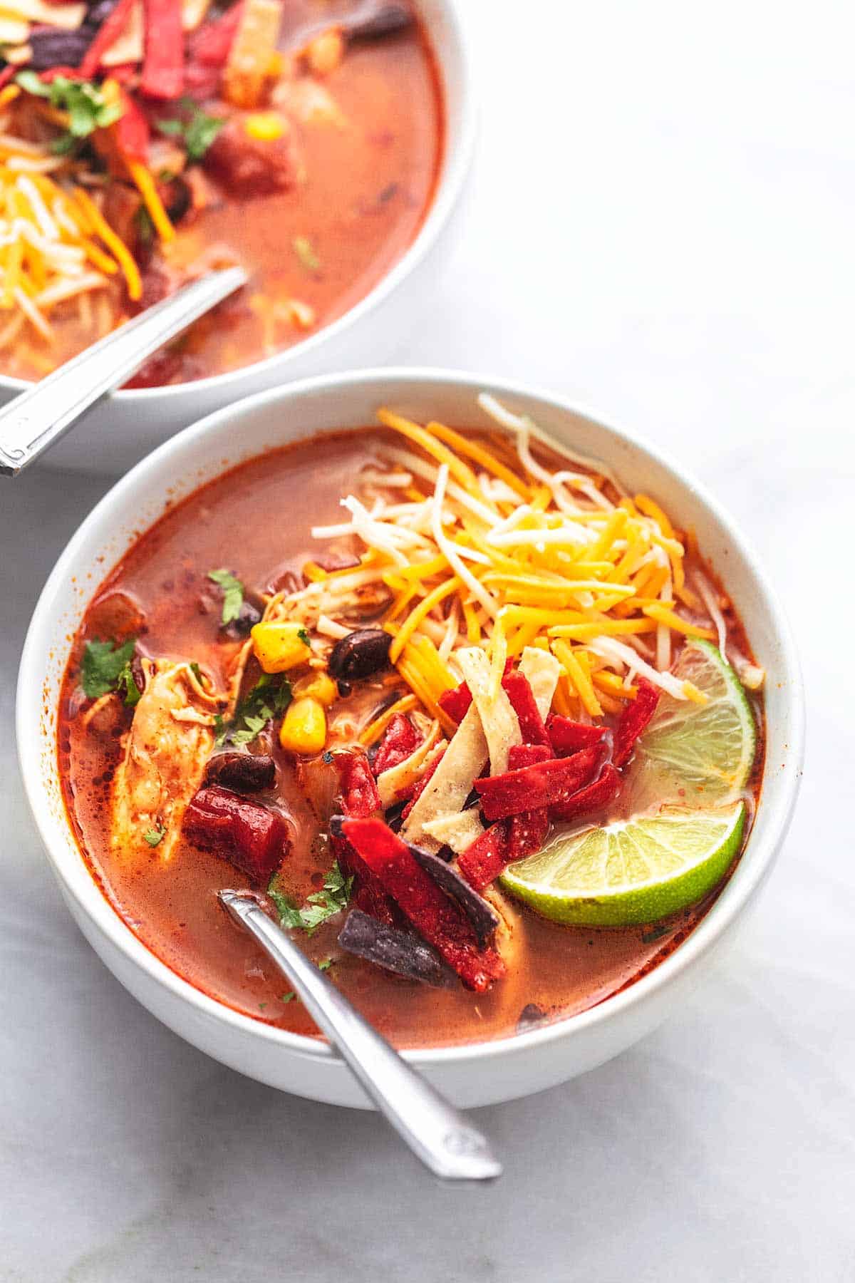 white bowl with chicken tortilla soup with shredded cheese on top.