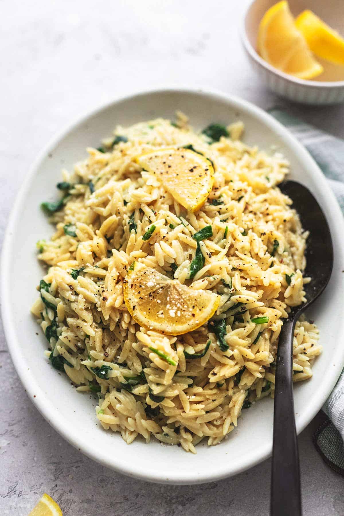 creamy parmesan spinach orzo with a serving spoon on a platter.