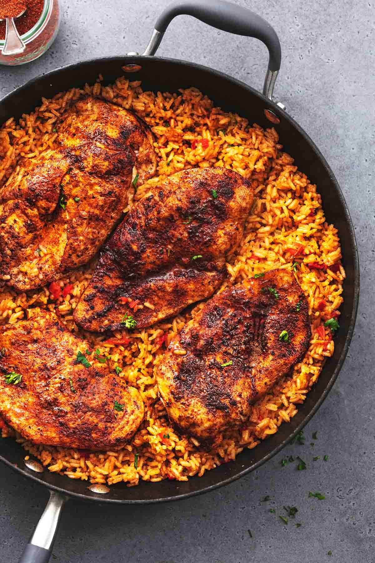 cooked blackened seasoned chicken breasts in skillet with rice with peppers