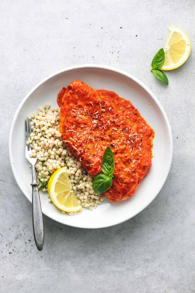 overhead view of chicken in orange sauce with couscous and lemon wedge on plate