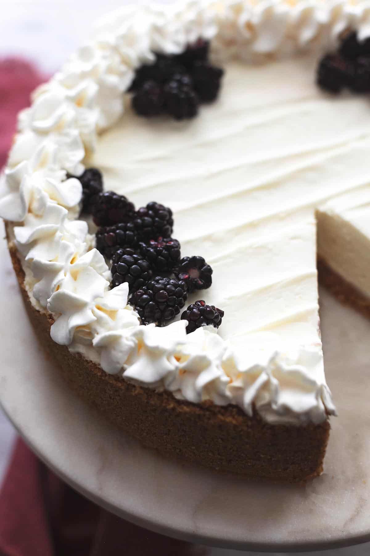 three quarters of a plain white cheesecake with whipped cream and graham cracker crust
