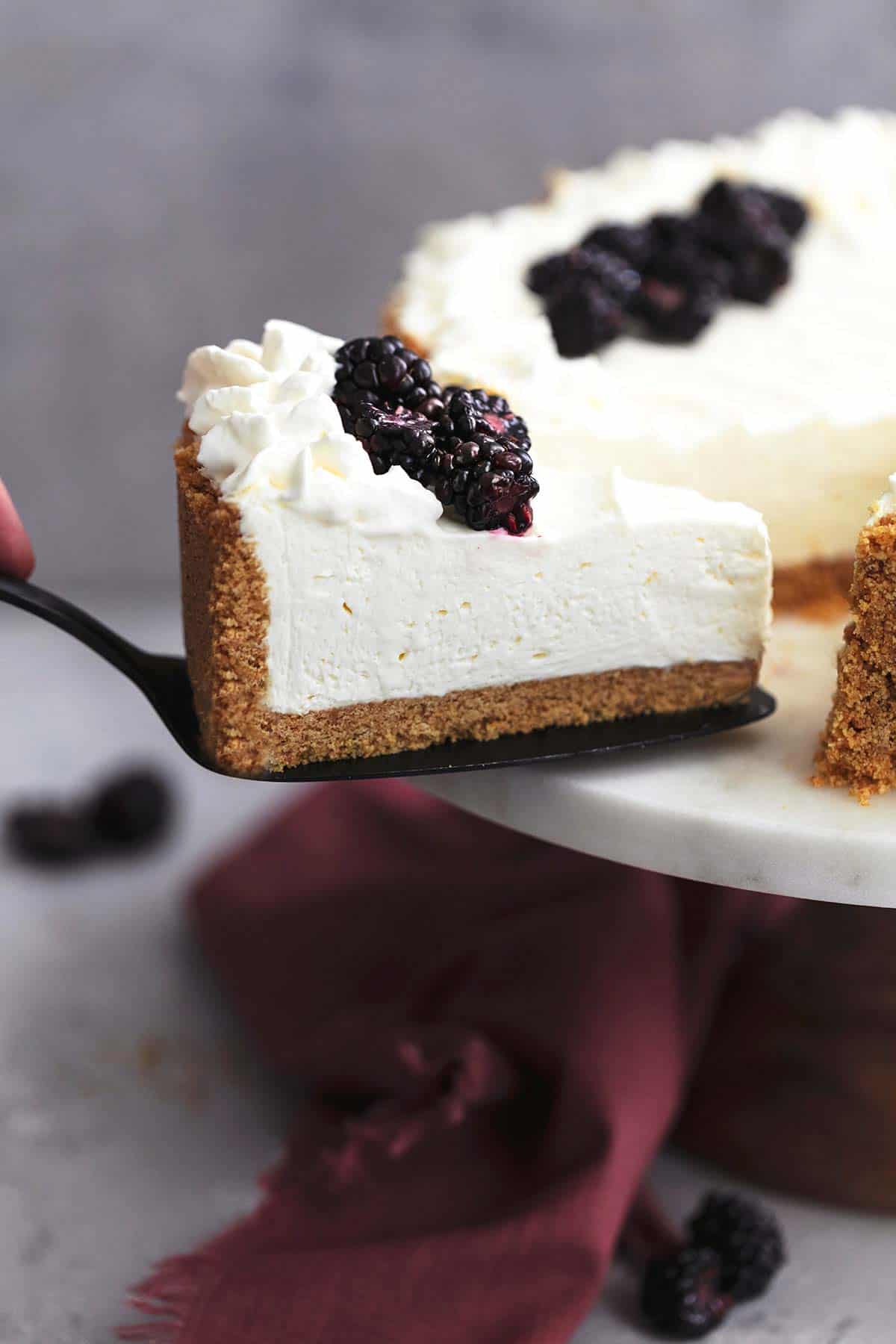 pie server lifting one slice of cheesecake from a cake stand with more cheesecake