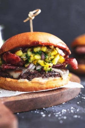hamburger with bacon, cheese, and pineapple relish on wood cutting board