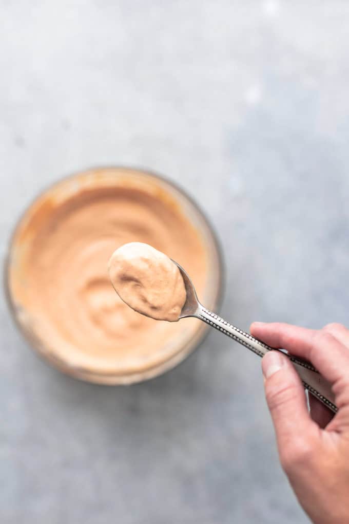 hand holding spoon full of sauce above bowl of additional sauce