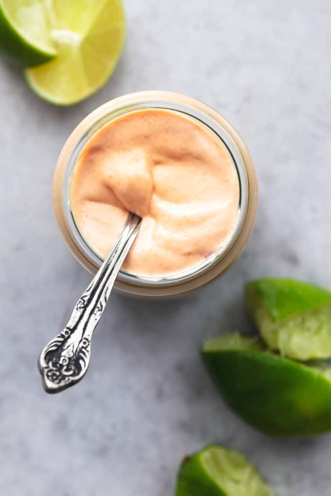 creamy sauce in jar with spoon and limes on table