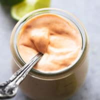 fish tacos sauce in a jar with a spoon and limes in background