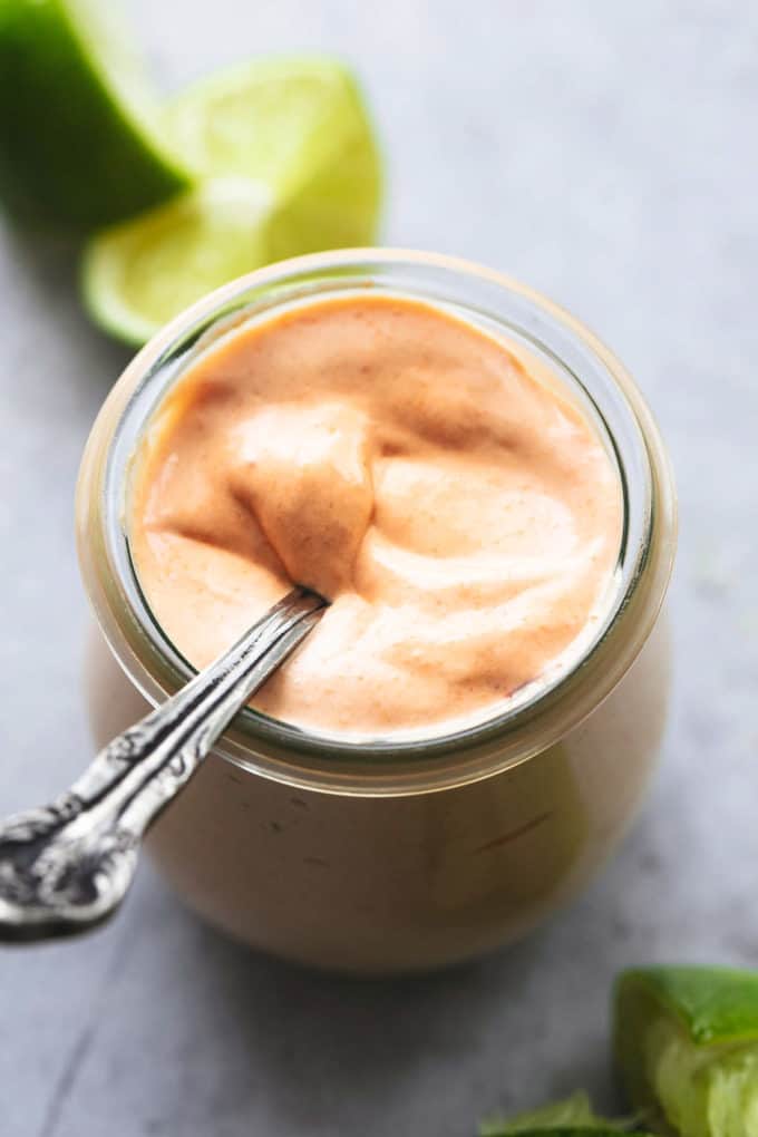 fish tacos sauce in a jar with a spoon and limes in background